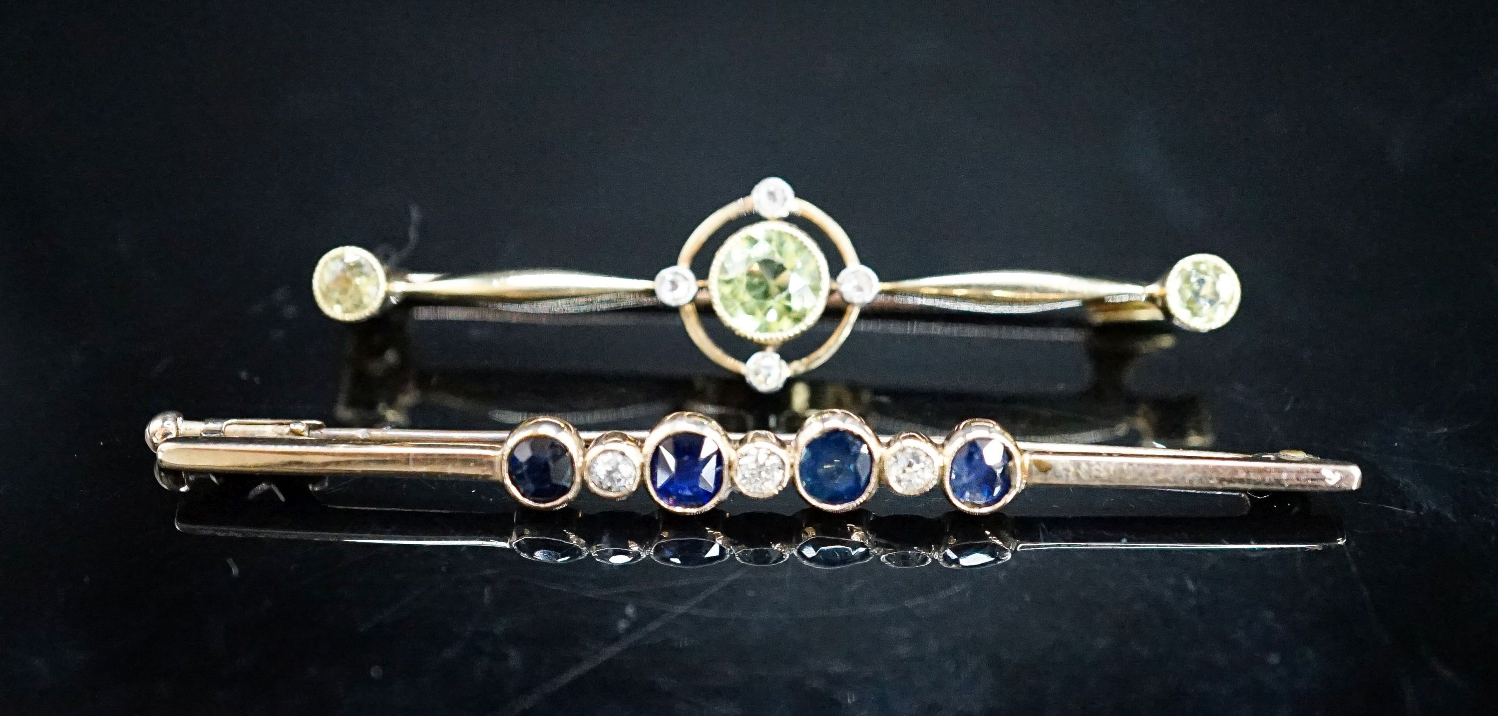 An Edwardian 15ct, peridot and diamond set bar brooch, 49mm, gross weight 4.4 grams and a yellow metal, sapphire and diamond set seven stone bar brooch, gross 3 grams